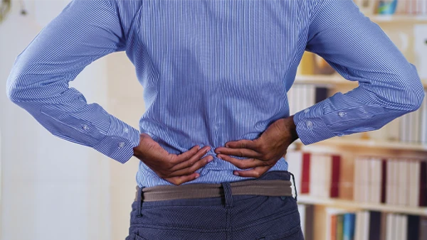 Man holding his lower back, indicating back pain.